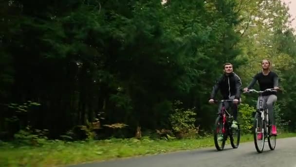 Atractiva pareja caminando con bicicletas y agua potable en el bosque — Vídeos de Stock