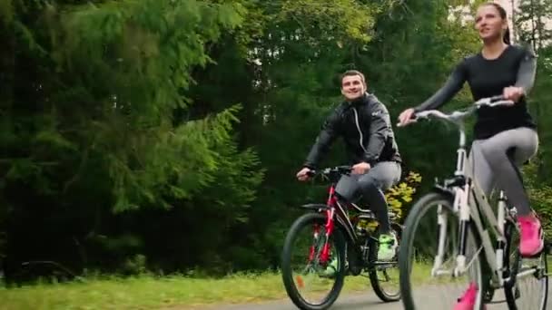 Atractiva pareja caminando con bicicletas y agua potable en el bosque — Vídeos de Stock