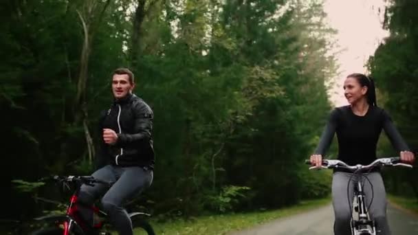 Steadicam disparo de bicicleta de montaña pareja montar en bicicleta sendero al atardecer haciendo alto . — Vídeo de stock