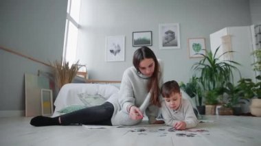 Anne ile küçük oğlu ile birlikte jigsaw puzzle toplamak için bir çocuk evinin beyaz iç. Mutlu aile, eğitim oyunları.