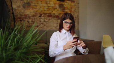 Güzel gülümseme kafede, onun resmi hücre telefon için serbest zaman sırasında kafede dinlenirken izlerken mutlu beyaz kadın dinlenme sırasında cep telefonu üzerinde iyi haber okuma ile büyüleyici kadın.