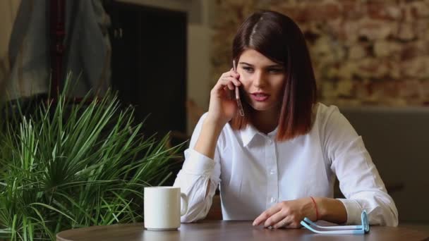 Gelukkig jonge vrouw zittend op de Bank in gezellige doeken met kop koffie — Stockvideo