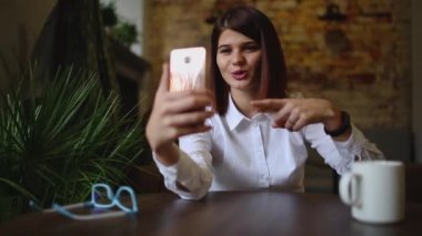 Kafede kahve yudumlarken akıllı telefon video sohbet konuşurken gülümseyen kız