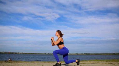 Koşucu kadın bacak egzersizleriyle bacaklarını esnetiyor. Fitness bayan sporcusu sahilde dinleniyor. Güç antrenmanından önce ısınıyor..