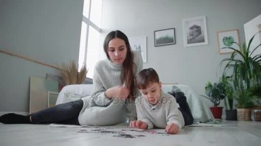 Anne ile küçük oğlu ile birlikte jigsaw puzzle toplamak için bir çocuk evinin beyaz iç. Mutlu aile, eğitim oyunları.