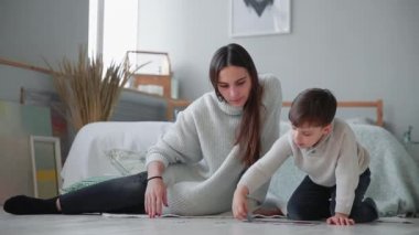 Anne ile küçük oğlu ile birlikte jigsaw puzzle toplamak için bir çocuk evinin beyaz iç. Mutlu aile, eğitim oyunları.