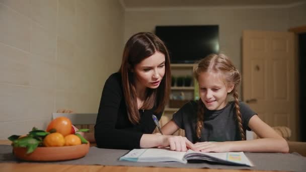 Mor och dotter gör en skola hemuppgift. Mamma hjälper till att ta itu med det. — Stockvideo