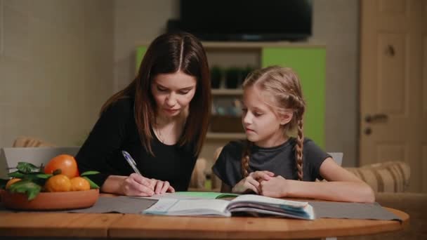 Mor och dotter gör en skola hemuppgift. Mamma hjälper till att ta itu med det. — Stockvideo