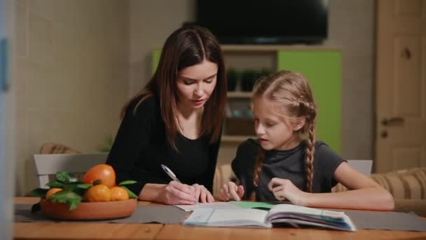 Mor och dotter gör en skola hemuppgift. Mamma hjälper till att ta itu med det. — Stockvideo