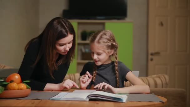 Mor och dotter gör en skola hemuppgift. Mamma hjälper till att ta itu med det. — Stockvideo