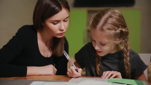 Μητέρα και κόρη κάνουν μια σχολική εργασία. Η μαμά βοηθά να ασχοληθεί με το θέμα. — Αρχείο Βίντεο