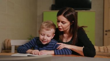 Anne ve oğlu evinin mutfağında oturan ve kitap okumayı öğrenme.