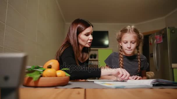 母と娘の学校の宿題をやっています。お母さんはそれに対処するのに役立ちます. — ストック動画