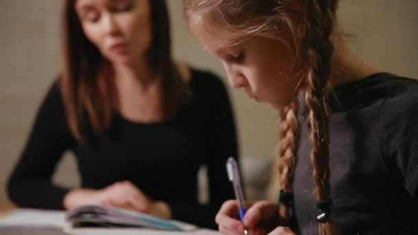 Matka i córka robi praca domowa szkoła. Mama pomaga radzić sobie z nim. — Wideo stockowe