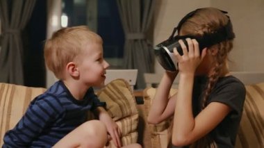 Kardeş kardeş evde ile sanal gerçeklik gözlükle oyun oynarken kanepede oturuyor. Mutlu bir aile