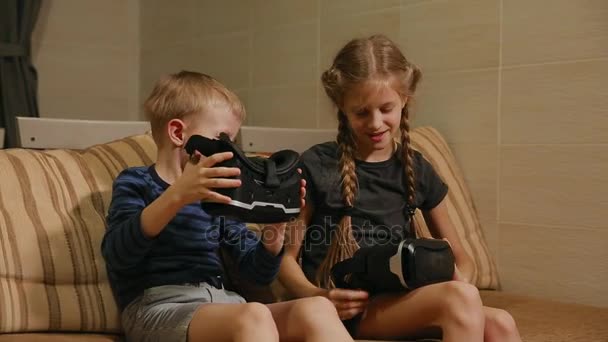 Broer met zuster thuis zitten op de Bank spelen van het spel met behulp van virtual reality bril. Gelukkige familie — Stockvideo