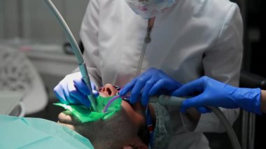 Diş hekimi ve hemşire hasta bir adamın bir diş tamiri. Matkap diş ve diş çürüğü ve sızdırmazlık kaldırmak için bormashenko kullanımı.