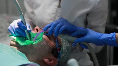 Diş hekimi ve hemşire hasta bir adamın bir diş tamiri. Matkap diş ve diş çürüğü ve sızdırmazlık kaldırmak için bormashenko kullanımı.