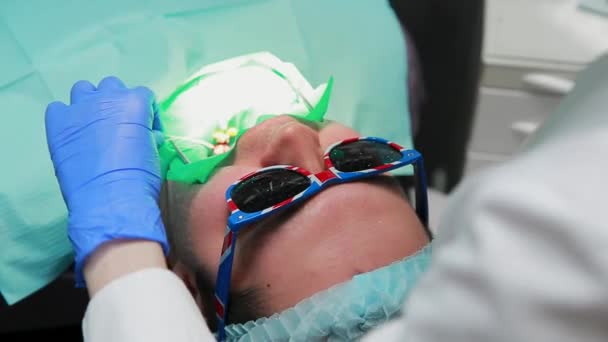 O dentista e a enfermeira a reparar um dente de um homem paciente. O uso de bormashenko para perfurar os dentes e remover a cárie dentária e vedação . — Vídeo de Stock