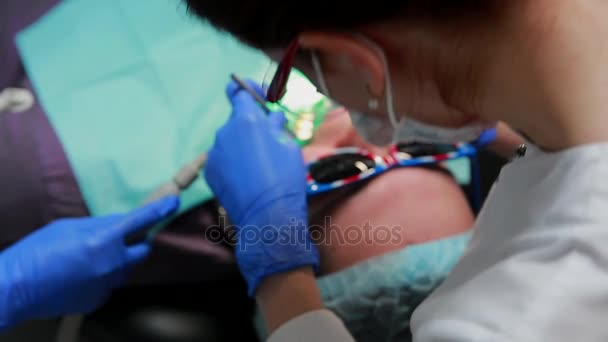 O dentista e a enfermeira a reparar um dente de um homem paciente. O uso de bormashenko para perfurar os dentes e remover a cárie dentária e vedação . — Vídeo de Stock