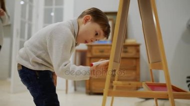 Küçük çocuk evin oturma odasında tahtada çizim childs işaretleri ile çizin. Okul öncesi eğitim. yakın çekim