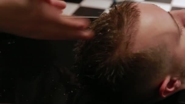 En kvinna tvättar håret i Barber shop skäggig man med schampo och balsam. Tvätta med schampo vattnet. — Stockvideo