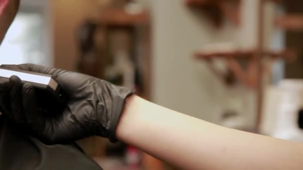 Een vrouw Kapper in de barbershop winkel om klanten man in een stoel en begint uit te voeren zijn kapsel. — Stockvideo