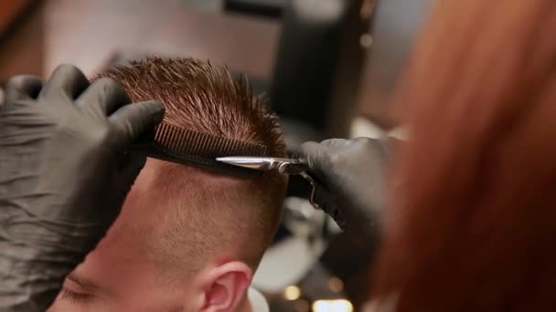 Une femme Barbier dans le salon de coiffure pour mettre les clients homme dans une chaise et commence à conduire sa coupe de cheveux . — Video