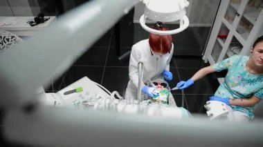 Diş hekimi ve hemşire hasta bir adamın bir diş tamiri. Matkap diş ve diş çürüğü ve sızdırmazlık kaldırmak için bormashenko kullanımı.