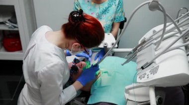 Diş hekimi ve hemşire hasta bir adamın bir diş tamiri. Matkap diş ve diş çürüğü ve sızdırmazlık kaldırmak için bormashenko kullanımı.