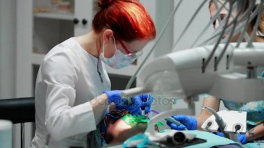 Diş hekimi ve hemşire hasta bir adamın bir diş tamiri. Matkap diş ve diş çürüğü ve sızdırmazlık kaldırmak için bormashenko kullanımı.