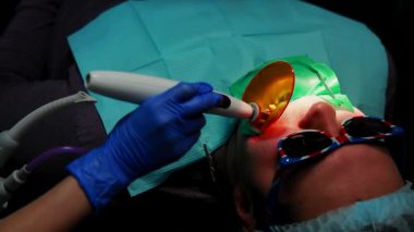 Kadın diş hekimi ve hemşirelik mühür diş bir ofis sandalye yalan hastaya ayarla.