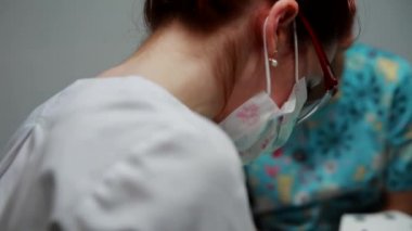 Kadın diş hekimi ve hemşirelik mühür diş bir ofis sandalye yalan hastaya ayarla.