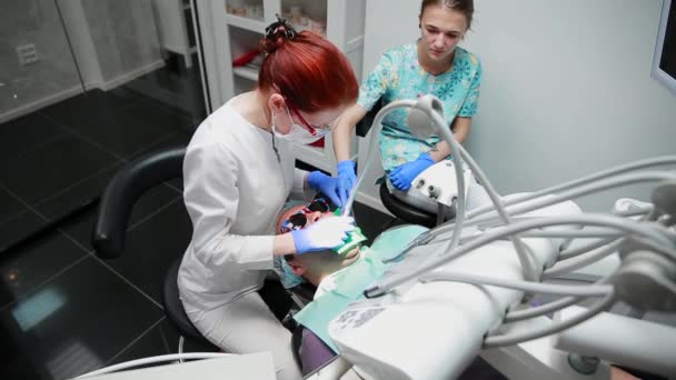 El dentista y la enfermera reparando un diente de un hombre paciente. El uso de bormashenko para taladrar los dientes y eliminar la caries dental y el sellado . — Vídeos de Stock