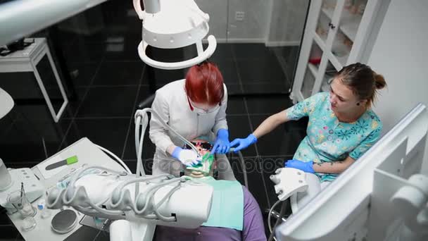 Дантист и медсестра чинят зуб пациенту. Использование бормашенко для сверления зубов и удаления кариеса и герметизации . — стоковое видео