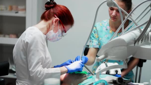 O dentista e a enfermeira a reparar um dente de um homem paciente. O uso de bormashenko para perfurar os dentes e remover a cárie dentária e vedação . — Vídeo de Stock