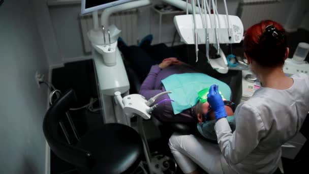 Eine Frau hält einen Zahnarzt in der Hand, der Patientenzähne bohrt und die Reste des Zahnes in der Zahnarztpraxis umzäunt. — Stockvideo