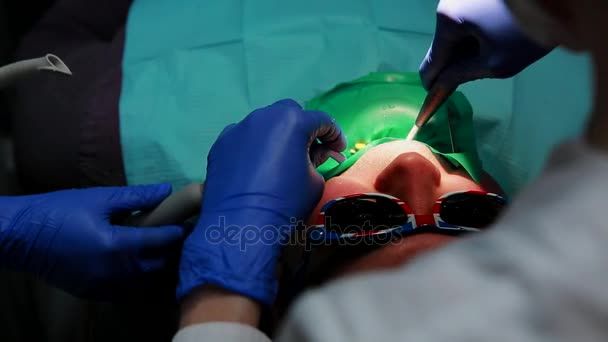 Una donna tiene un dentista che trivella i pazienti dente e la recinzione i resti del dente nello studio dentistico . — Video Stock