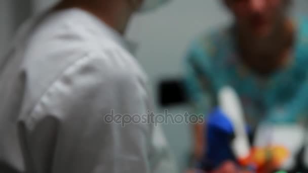 O femeie dentist și asistenta ei au pus sigiliul pacientului întins pe scaunul unui cabinet stomatologic. . — Videoclip de stoc