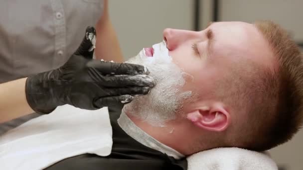 Szczegół twarz człowieka rozprzestrzeniania pianki do golenia. Fryzjer, salon fryzjerski. — Wideo stockowe