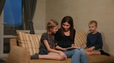 Anne kızı ve onları kendi oturma odasında kanepede otururken bir hikaye okuma genç oğlu ile kanepede oturan.