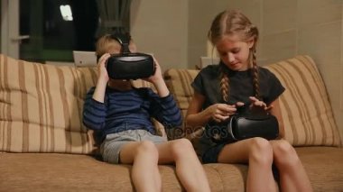 Kardeş kardeş evde ile sanal gerçeklik gözlükle oyun oynarken kanepede oturuyor. Mutlu bir aile
