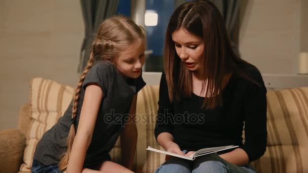 Μητέρα και κόρη κάνουν μια σχολική εργασία. Η μαμά βοηθά να ασχοληθεί με το θέμα. — Αρχείο Βίντεο