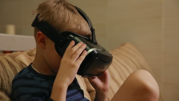 Niño 6-7 años jugando en casa con la ayuda de gafas de realidad virtual videojuegos. Primer plano — Vídeos de Stock