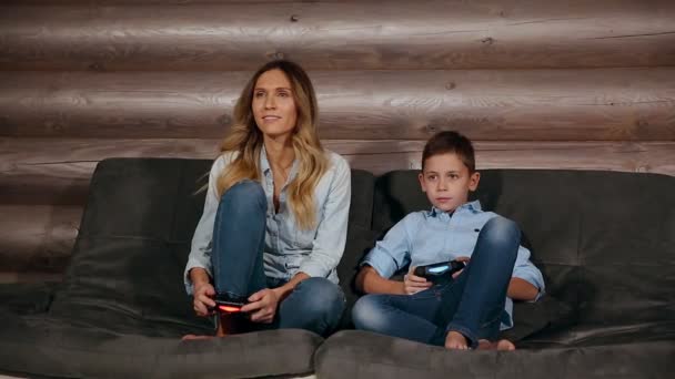 Mooie moeder met haar zoon spelen van video games op de console van het gokken in de woonkamer van zijn huis. Gelukkige familie in een country house. — Stockvideo