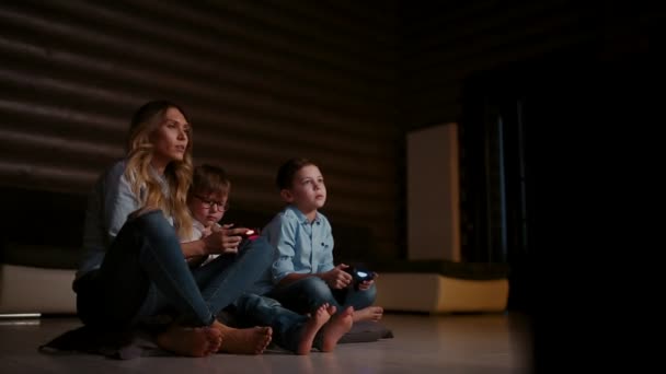 Bela mãe com seu filho jogando videogames no console de jogos na sala de estar de sua casa. Família feliz em uma casa de campo . — Vídeo de Stock