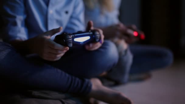 Close-up van handen met behulp van een draadloze joystick voor games op de console's nachts. Het licht van de Tv. Twee mensen. — Stockvideo