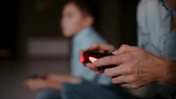 Les mains tenant un contrôleur à une console de jeu, et en arrière-plan, le garçon regarde le robinet et joue à des jeux vidéo. L'accent passe de l'un à l'autre . — Video