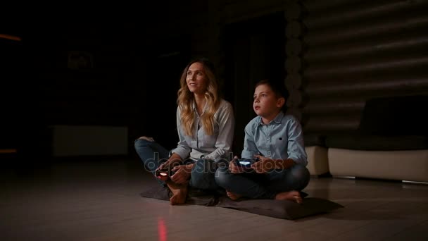 Hermosa madre con su hijo jugando videojuegos en la consola de juegos en la sala de estar de su casa. Familia feliz en una casa de campo . — Vídeos de Stock