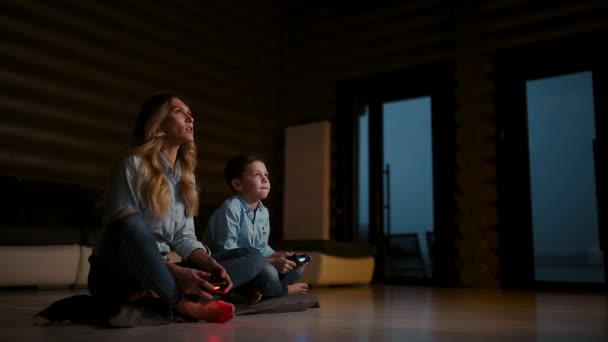 Gyönyörű anya a fiával videojátékok a játékkonzol a nappaliban a házból. Boldog család, egy vidéki házban. — Stock videók